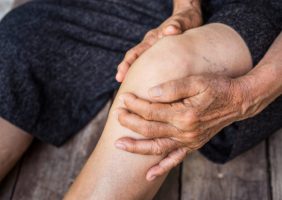 Image of a person holding knee with Osteoarthritis