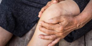Image of a person holding knee with Osteoarthritis