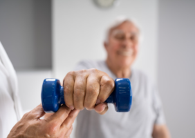 Elderly man with a hand therapist lifting a weight