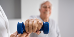 Elderly man with a hand therapist lifting a weight