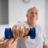 Elderly man with a hand therapist lifting a weight