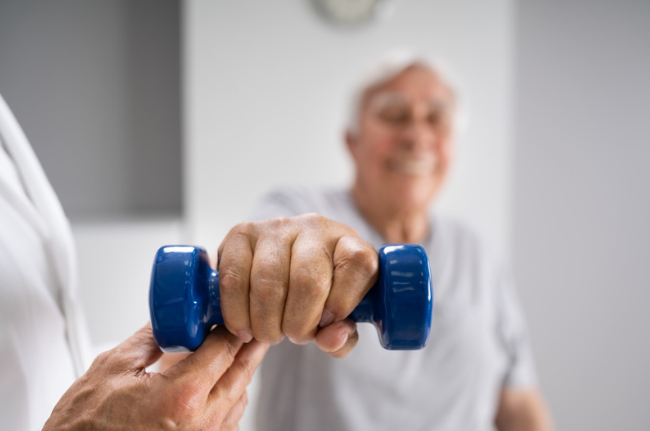 Elderly man with a hand therapist lifting a weight