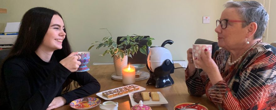 Granddaughter and grandmother sharing a conversation over a cup of tea