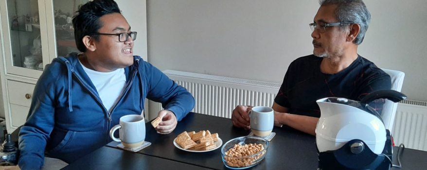 Father and son enjoying tea and biscuits in the dining room